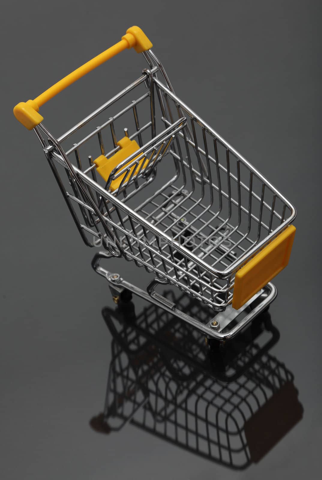 Image of an empty shopping cart and its shadows against a black background.