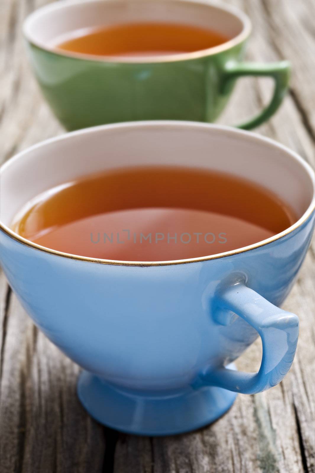 Two antiques cups with tea on a rustic background