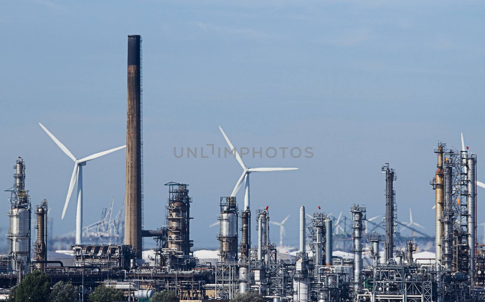 View on industrial pollution with modern windmills in background - polluting against clean energy