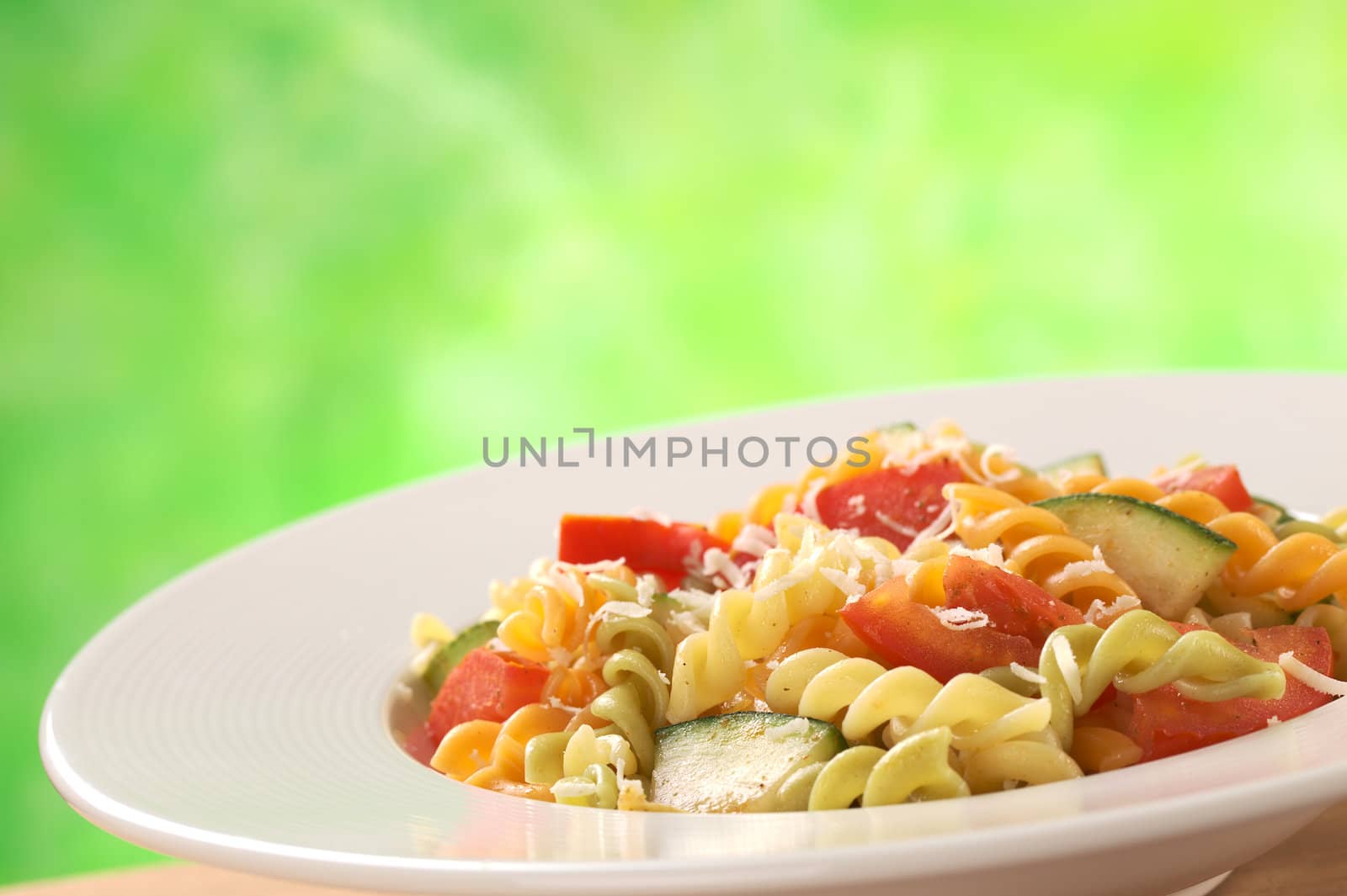 Colorful fusilli pasta with zucchini and tomato and grated cheese (Selective Focus, Focus one third into the meal)