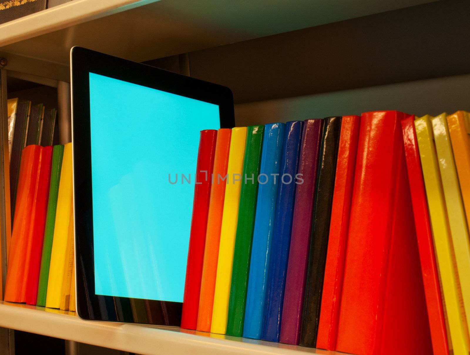 Row of colorful books and electronic book reader on the shelf