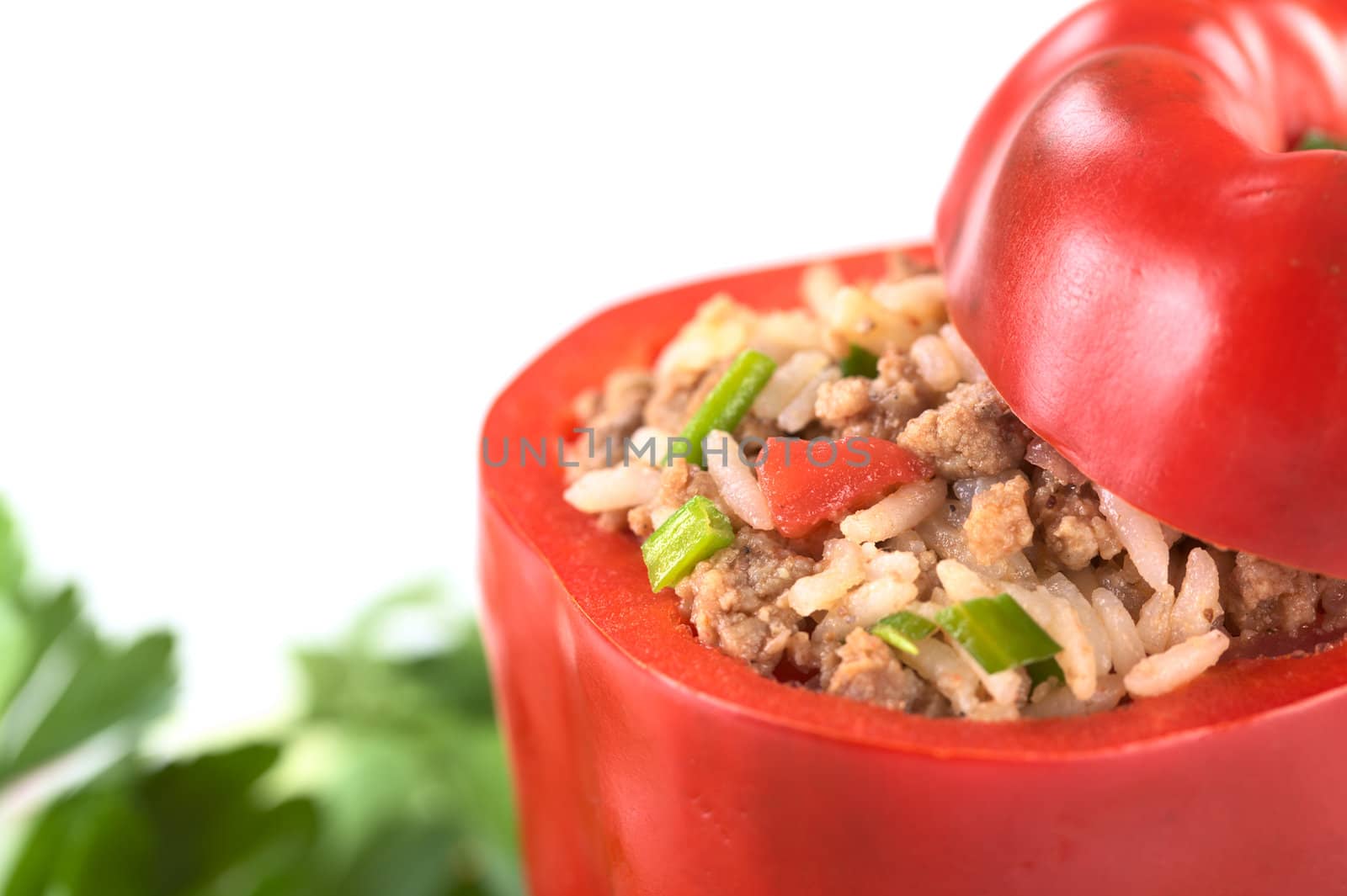 Unbaked stuffed red bell pepper filled with ground meat, onion, rice, tomato and green onion (Selective Focus, Focus on the tomato piece and the stuffing around it in the pepper) 