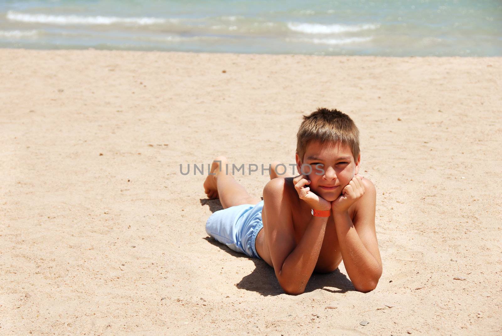 caucasian boy lying on the sand beach in Egypt