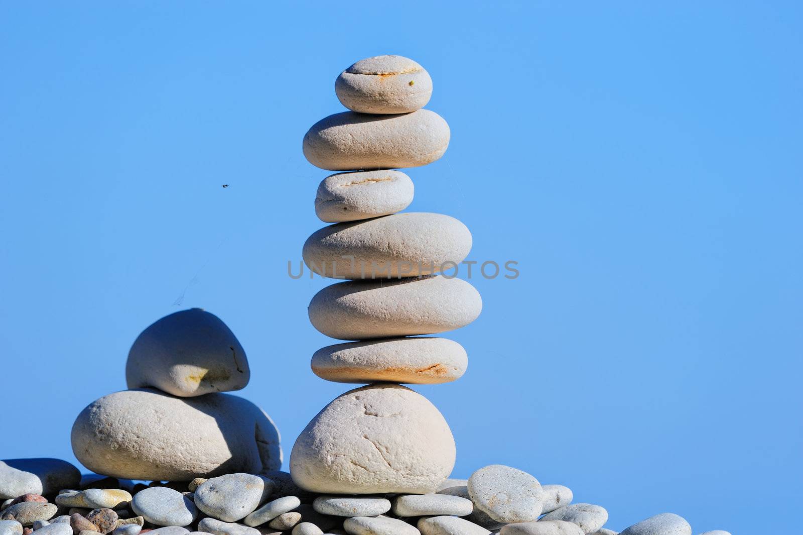 Balancing of piles of white pebbles near the sea
