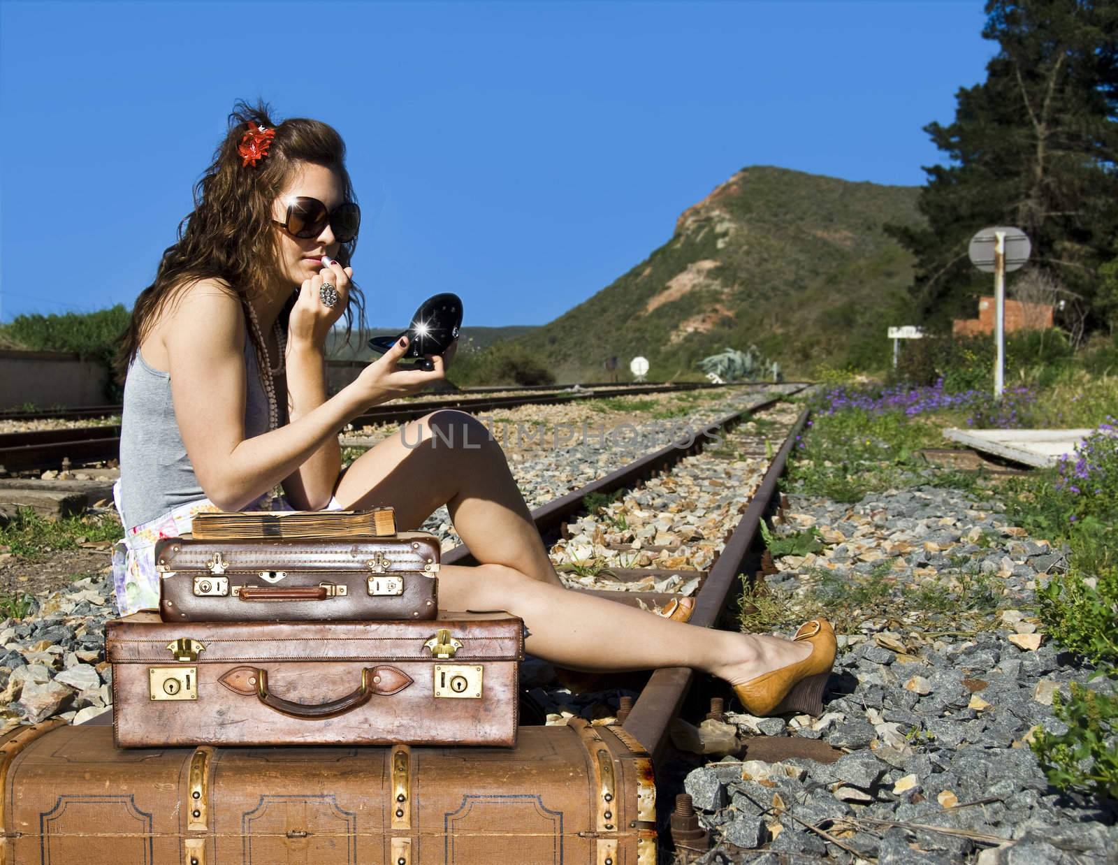 Young traveling woman with her suitcases on the railway tracks by tish1
