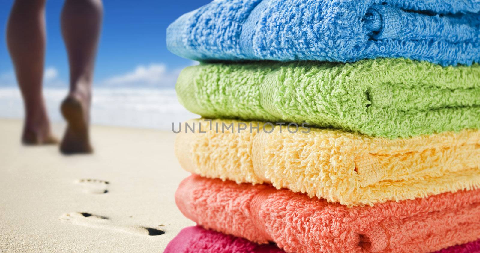 Colorful towels and someone walking on the beach