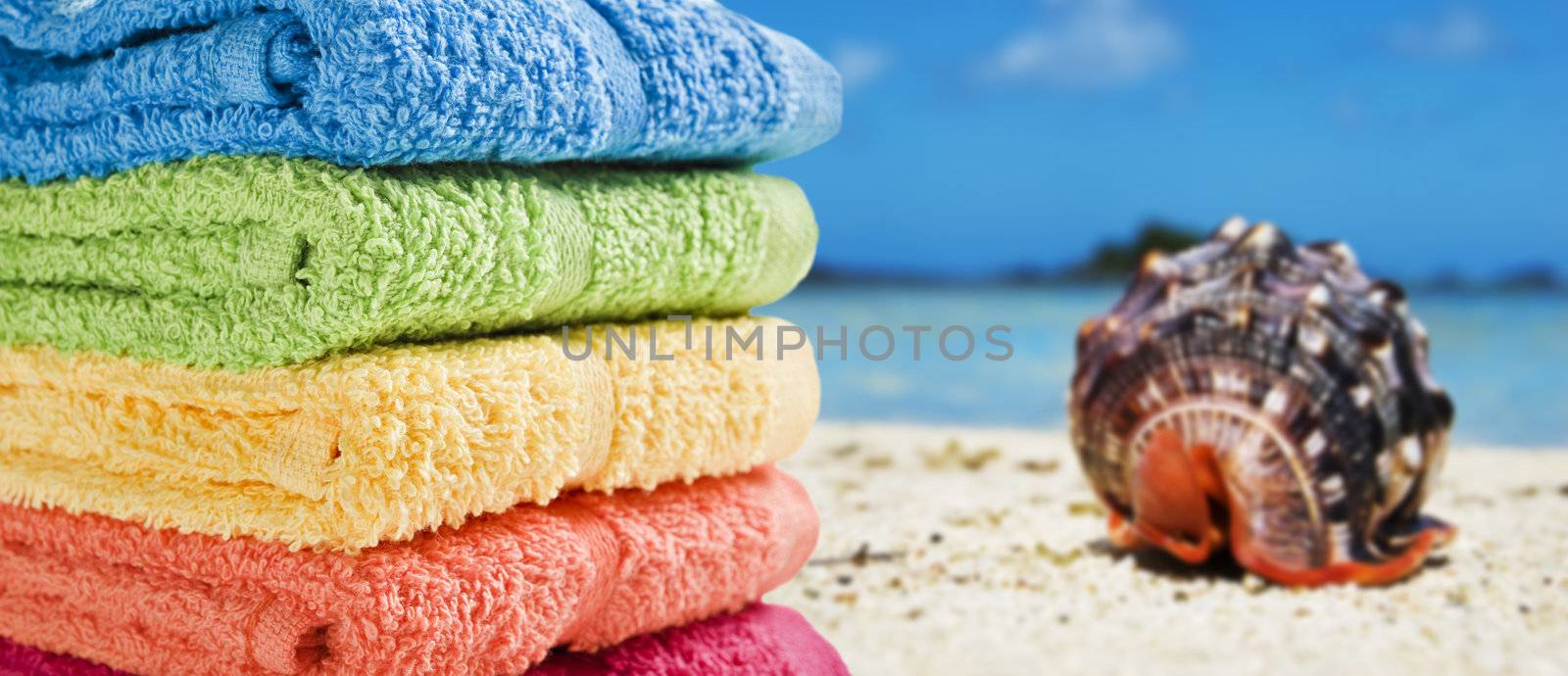 Colorful towels on a white beach with a beautiful sea shell