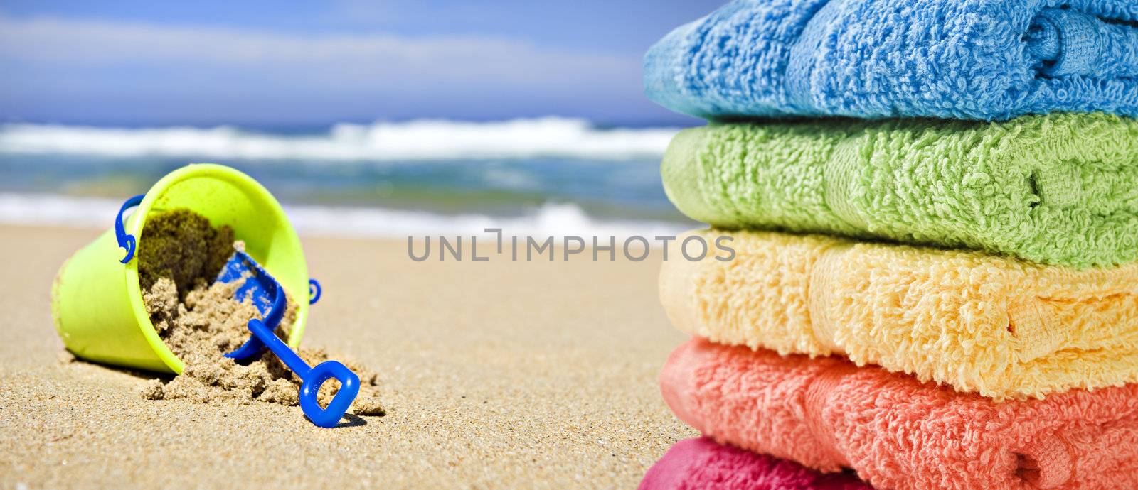 Colorful towels on a beach with toy bucket and spade by tish1