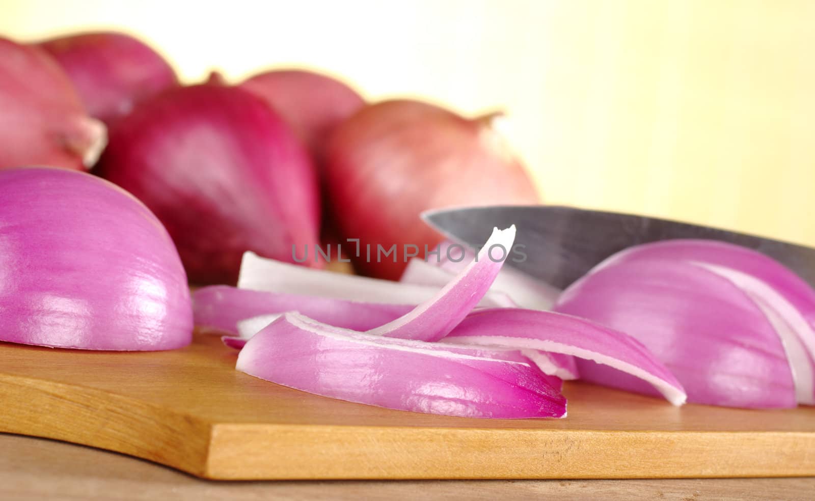 Cutting red onions on wooden cutting board (Selective Focus, Focus on the onion slices in the front)