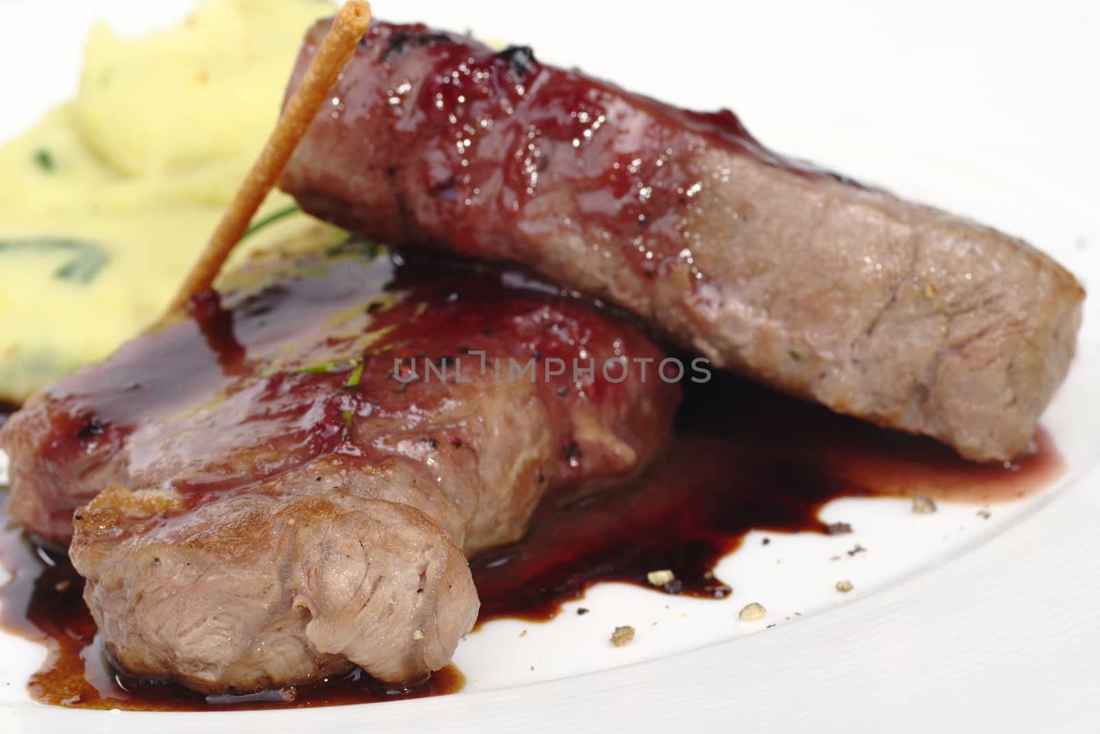 Main dish: Meat with red pepper sauce and mashed potato in the back (Selective Focus, Focus on the front of the left meat)