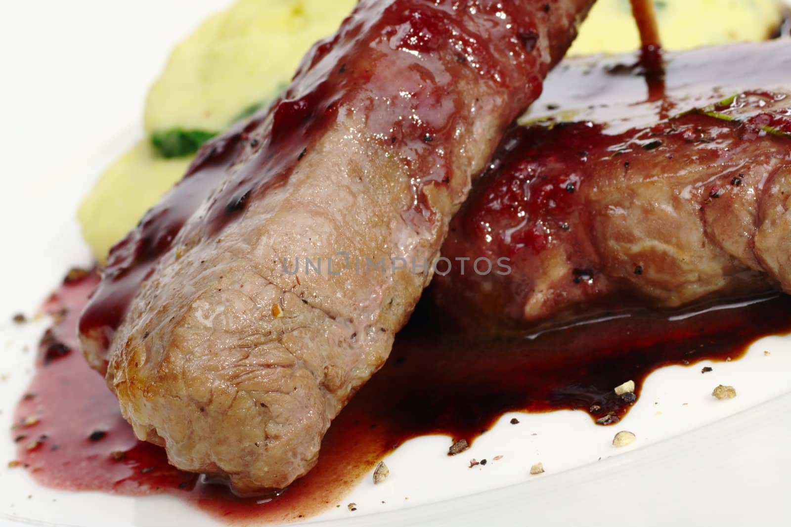 Main dish: Meat with red pepper sauce and mashed potato in the back (Selective Focus, Focus on the front of the left meat)