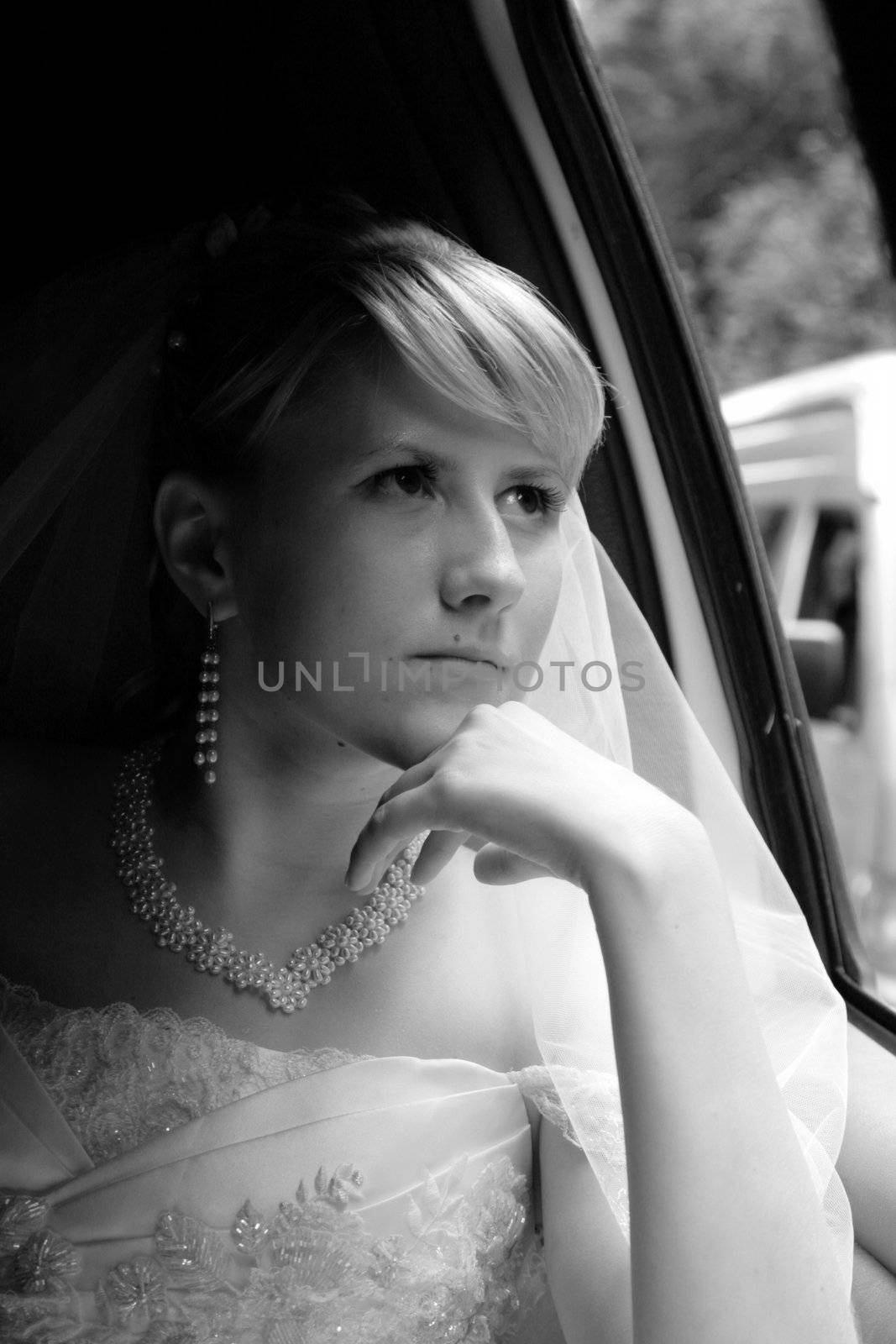 The thoughtful bride looks out of the window a limousine