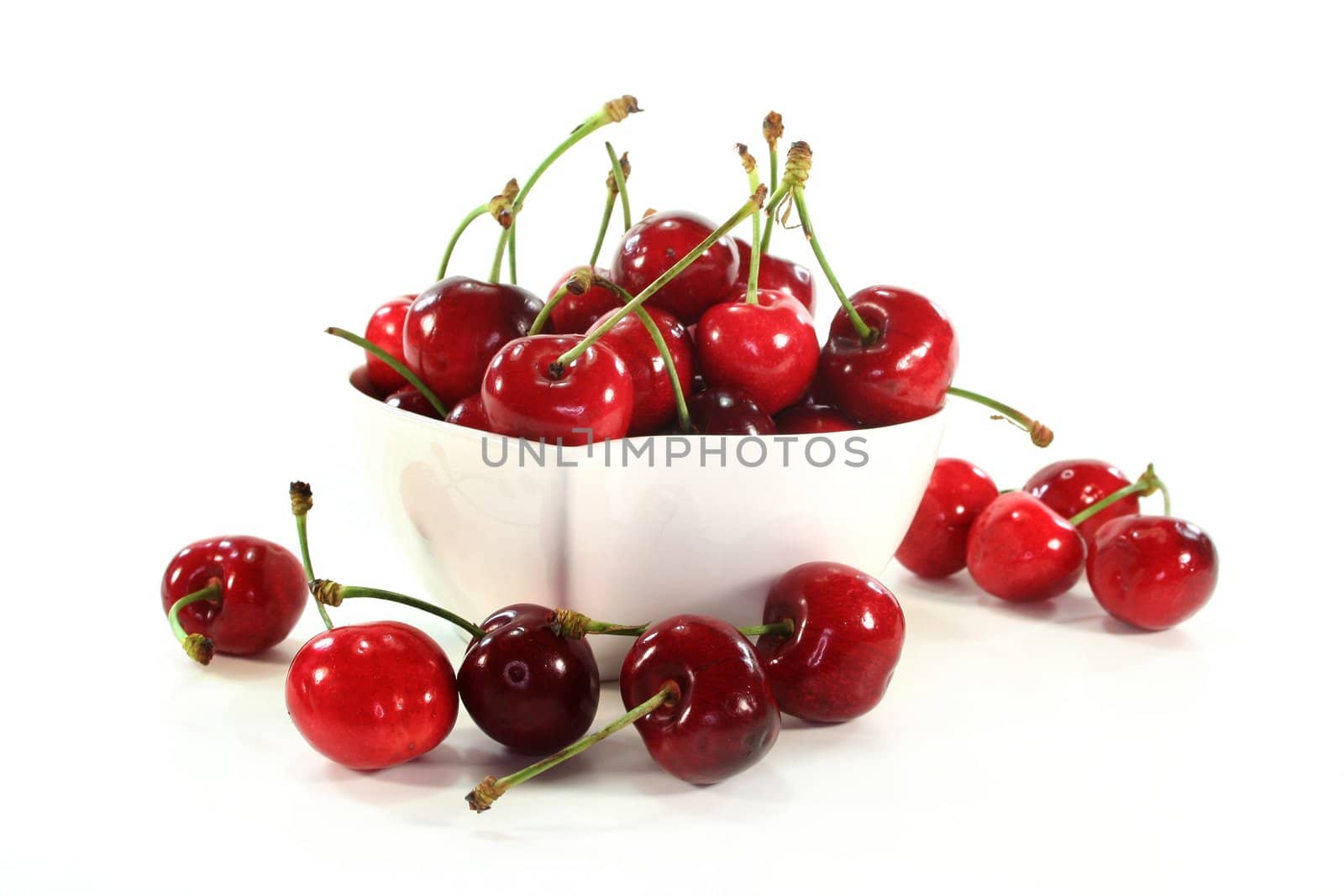 a white bowl filled with fresh cherries
