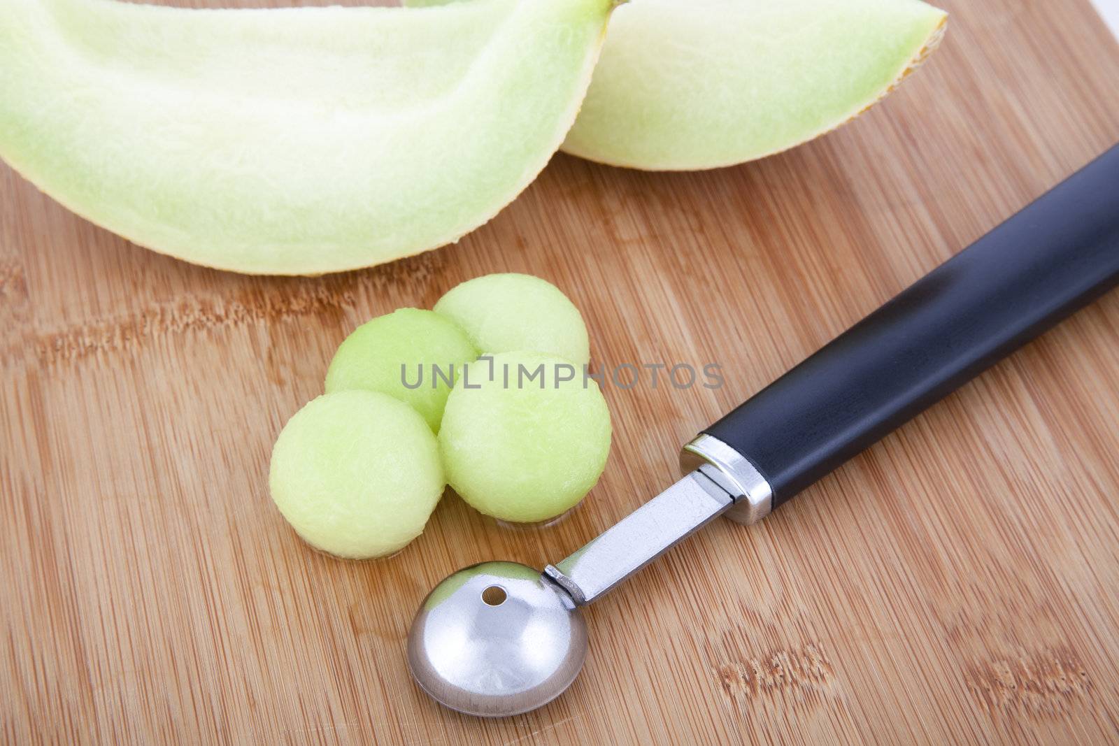Fresh Honeydew melon balls on cutting board with melon baller