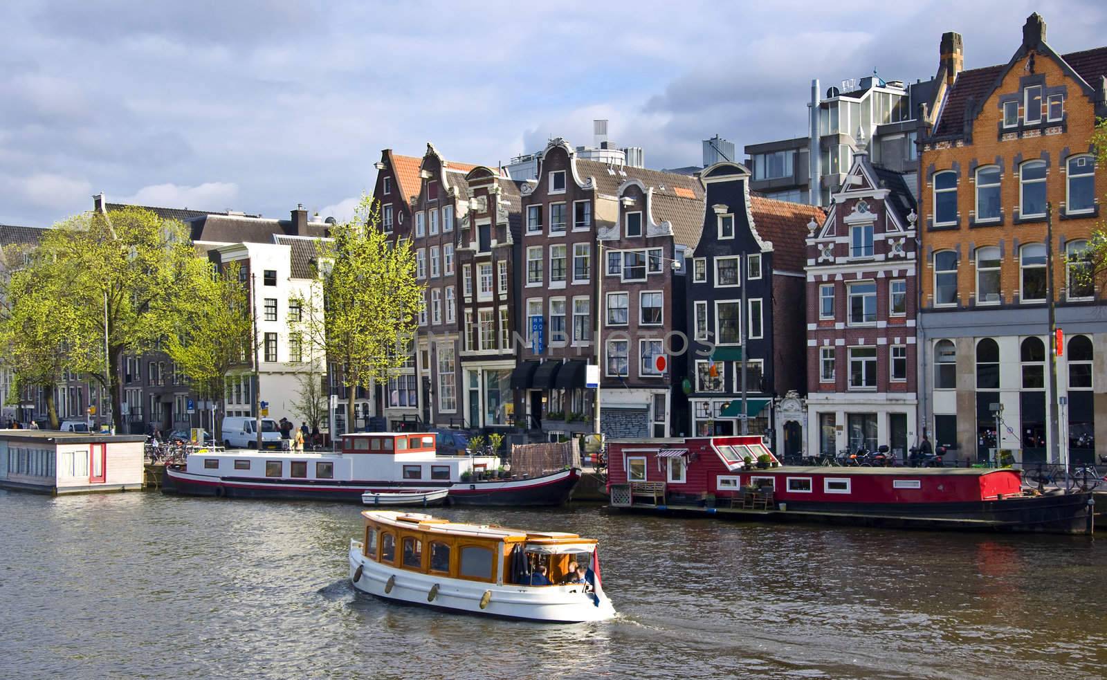 Classical Amsterdam view. Boat floats on the channel on the background of Dutch houses. Urban scene.