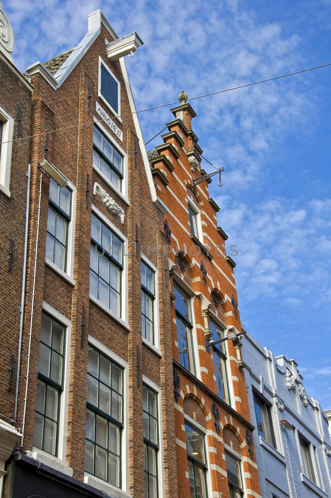 Amsterdam. Dutch houses with a hook at the blue sky. Urban environment of the historical city center.