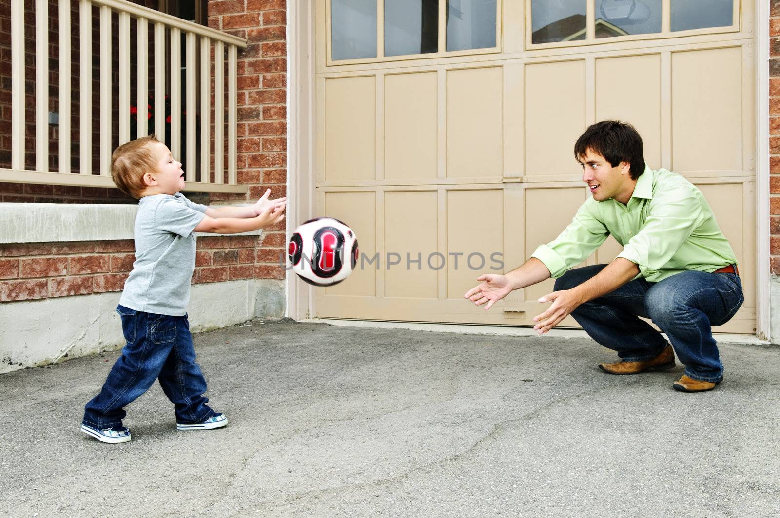 Father and son playing soccer by elenathewise