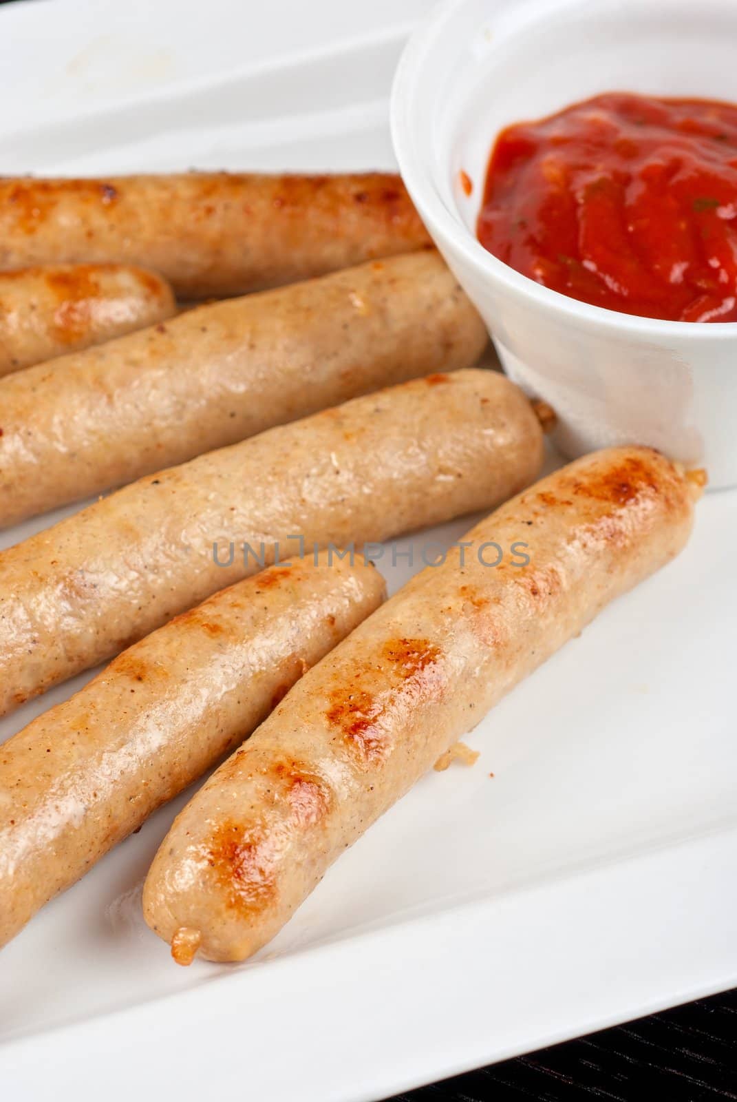 Grilled sausages with cabbage, greens and tomato sauce on white plate