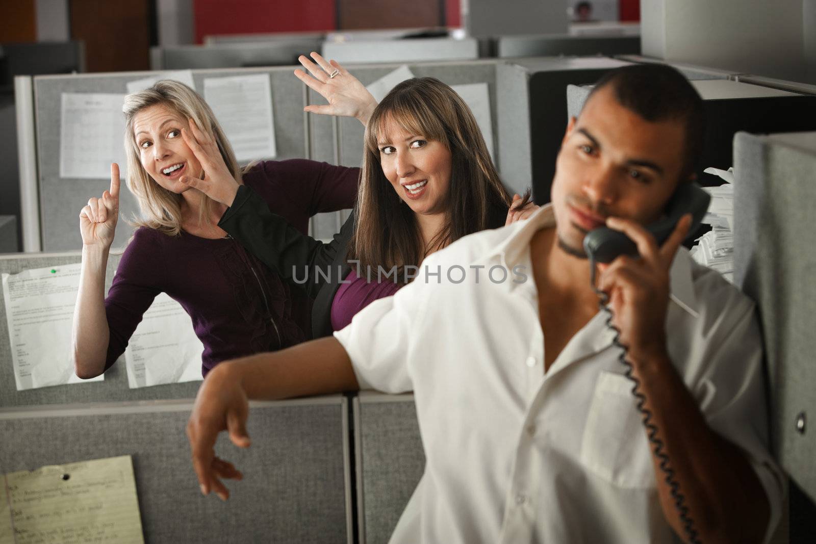 Two women flirting with a male coworker in the office 