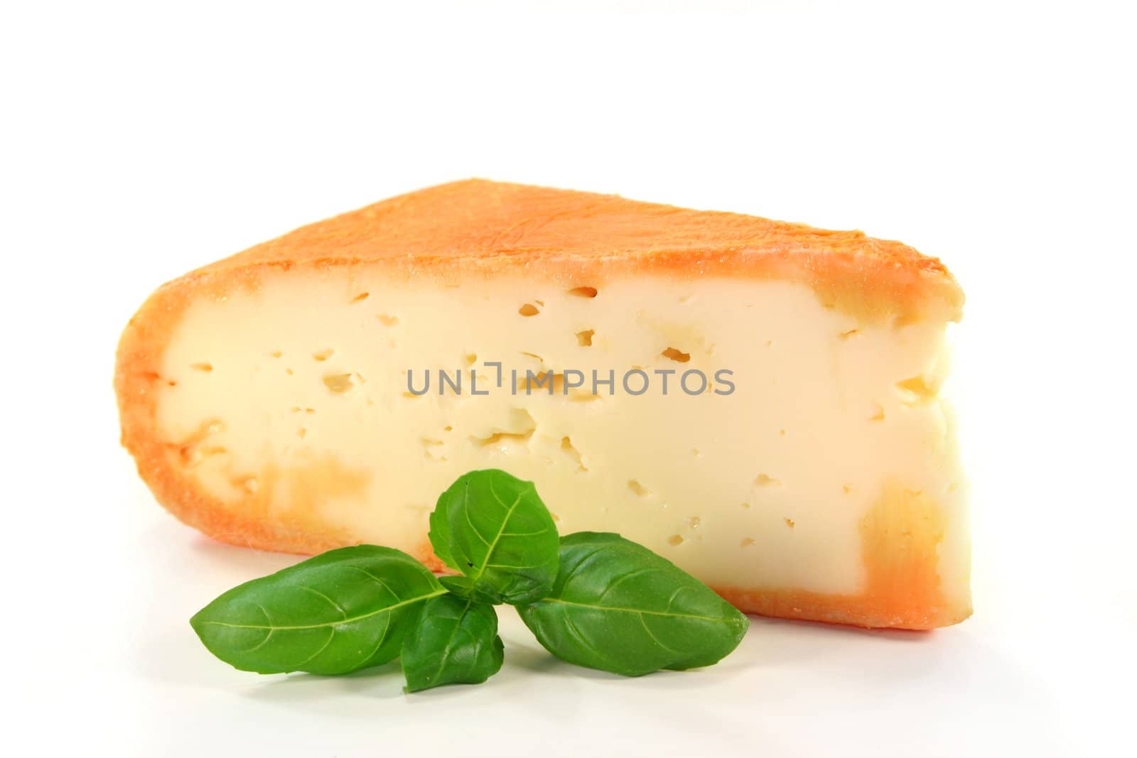 a piece of soft cheese with basil on a white background
