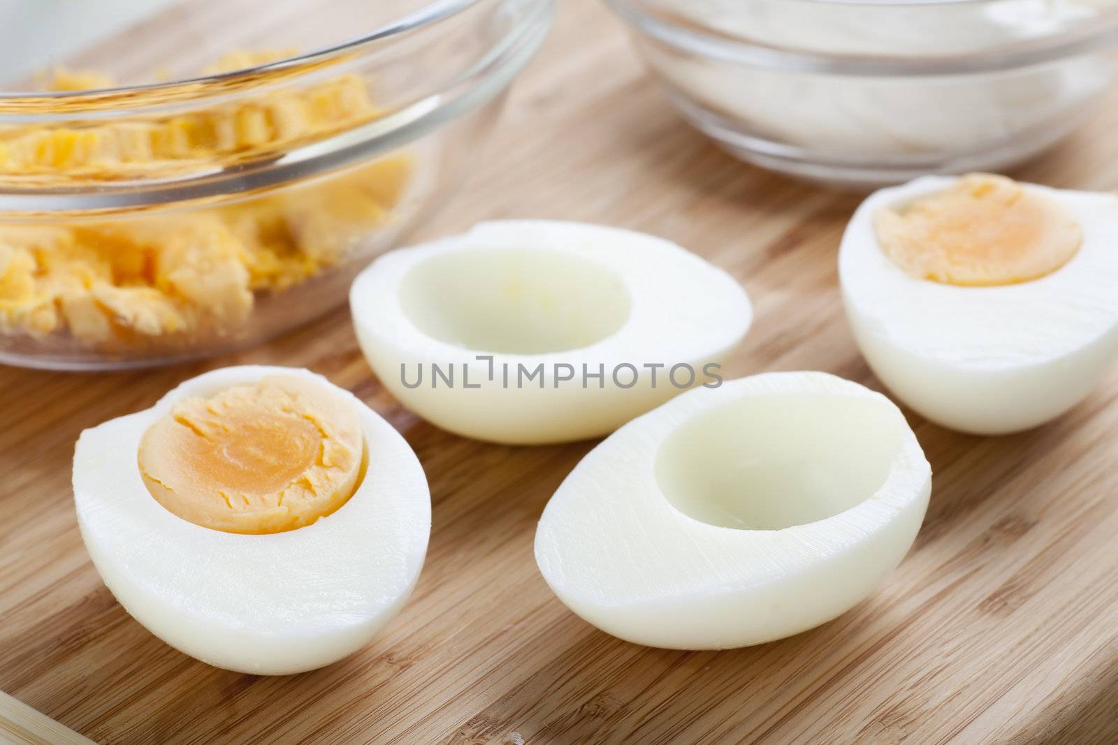 Two hard boiled eggs cut in half with yolk in bowl.