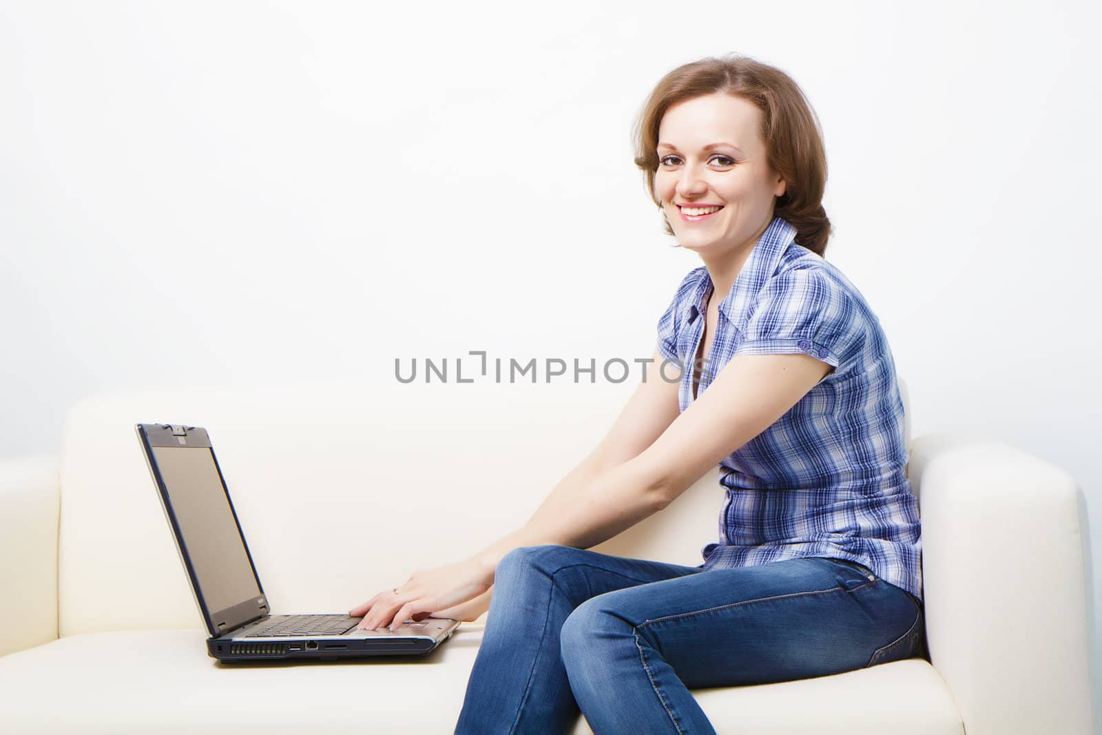 young slender woman with a laptop sitting on the couch