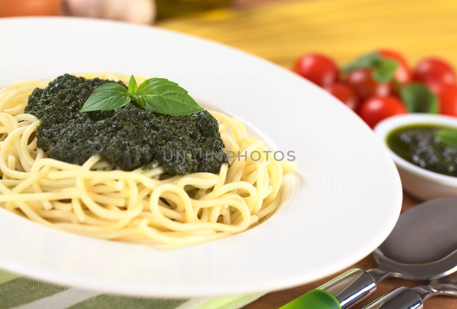Spaghetti with fresh pesto made of basil, garlic and olive oil garnished with basil leaf (Selective Focus, Focus on the basil leaf on the pesto)
