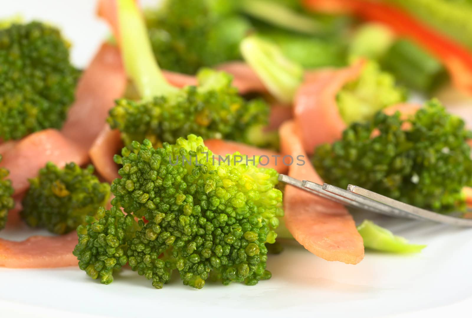 Fresh broccoli-ham salad with a fork on the side (Selective Focus, Focus on the broccoli floret in the front)