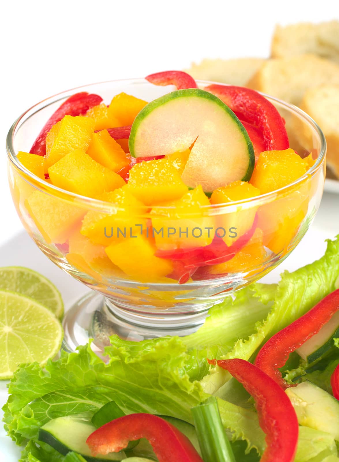 Fresh salad of mango, red bell pepper, cucumber and lettuce (Selective Focus, Focus on the cucumber slice in  the bowl)