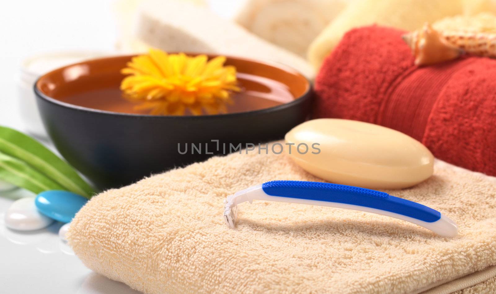 Disposable plastic shaver on towel with soap with other bath utensils in the back (Selective Focus, Focus on the shaver)