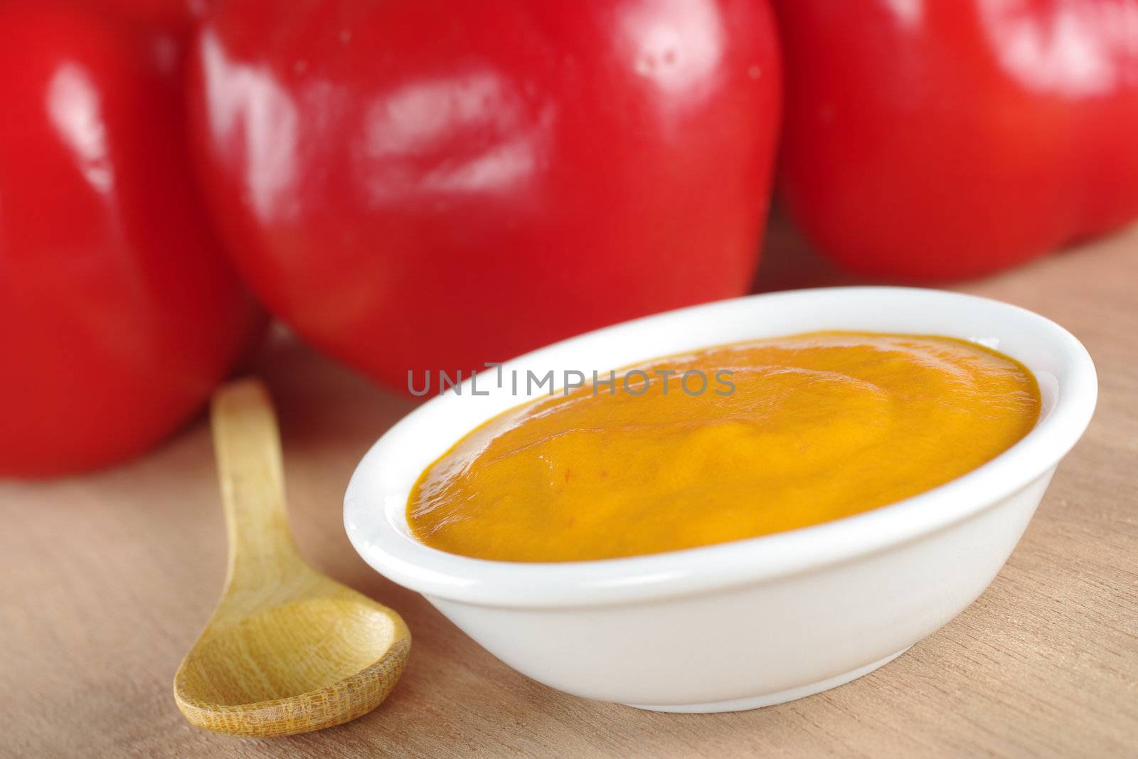 Peruvian hot salsa made of a red pepper called rocoto which is visible in the background (Selective Focus, Focus on the middle of the sauce)