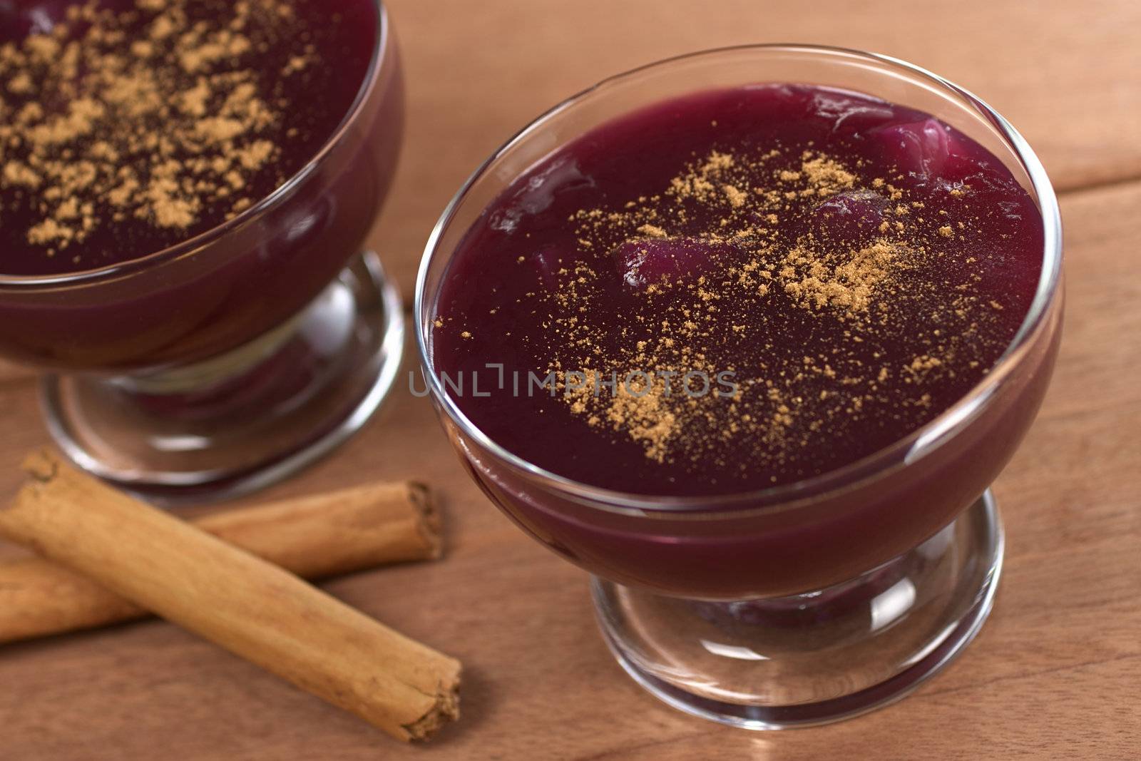 Popular Peruvian desserts called Mazamorra Morada (made out of purple corn) with cinnamon sticks (Selective Focus, Focus in the middle of the dessert in the front)