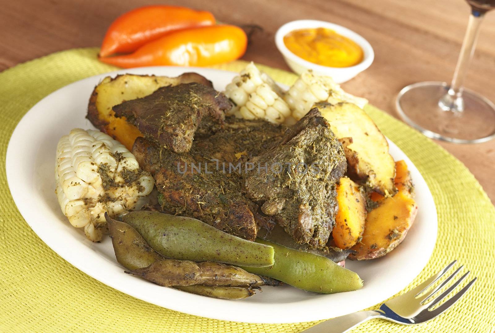 Traditional Peruvian food called Pachamanca which is from the Andean region. It consists of different kinds of meat covered with some herbs, broad beans (Spanish: habas), corn, potatoes and sweet potatoes. Traditionally it is cooked in the ground (Selective Focus, Focus on the beans and the front of the meat)