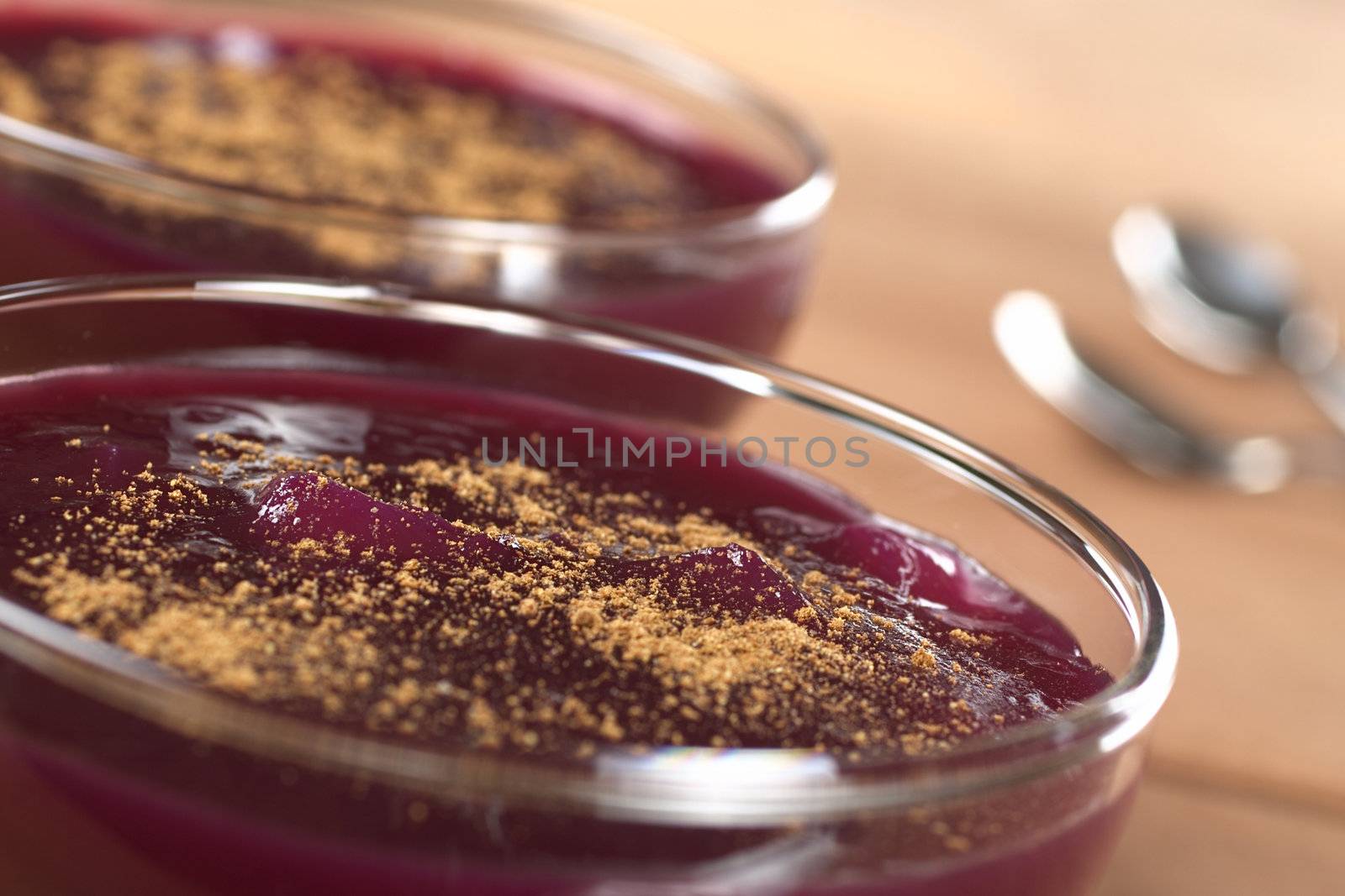 Popular Peruvian dessert called Mazamorra Morada, which is made from purple corn, fruits and spices and is garnished with cinnamon powder (Selective Focus, Focus on the middle of the first dessert)