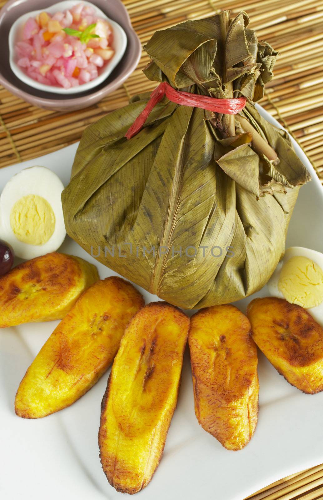 Traditional Peruvian food called Juane from the jungle area. It is a rice dish with meat and eggs covered by bijao leaves and served with fried plantains, eggs and olives (Selective Focus, Focus on the juane)