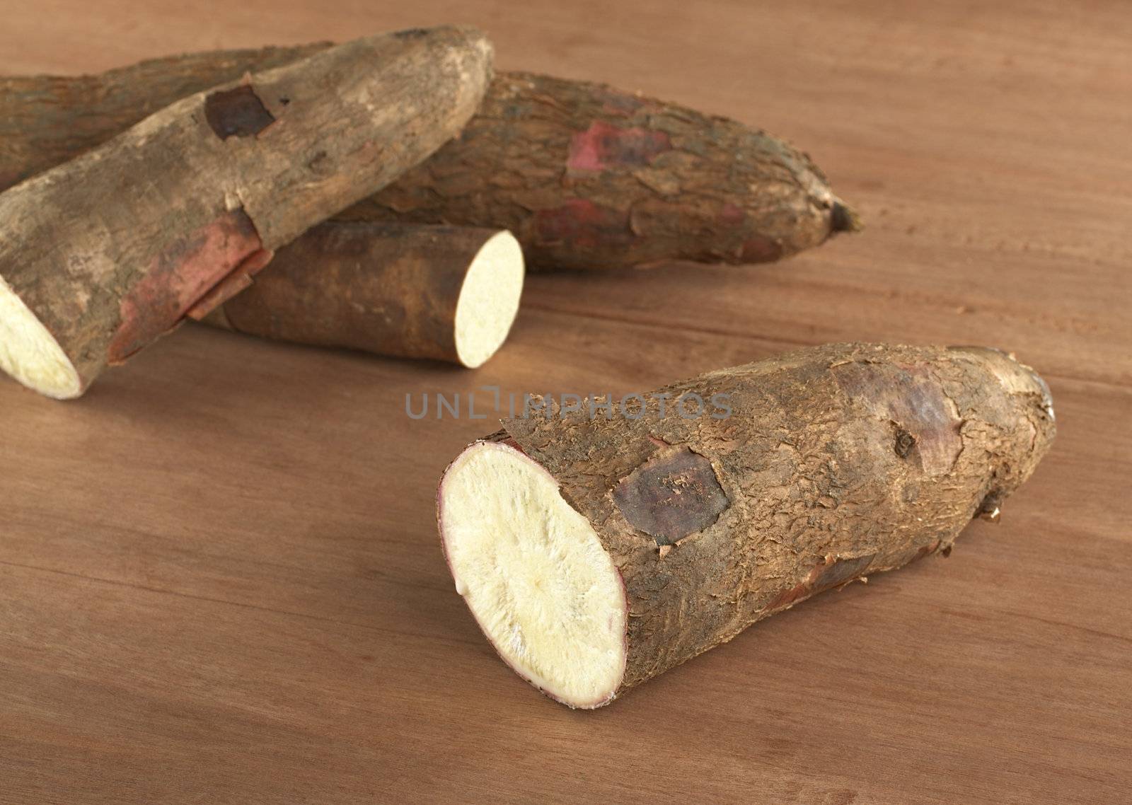 Raw cassava (lat. Manihot esculenta) on wood (Selective Focus, Focus on the front)