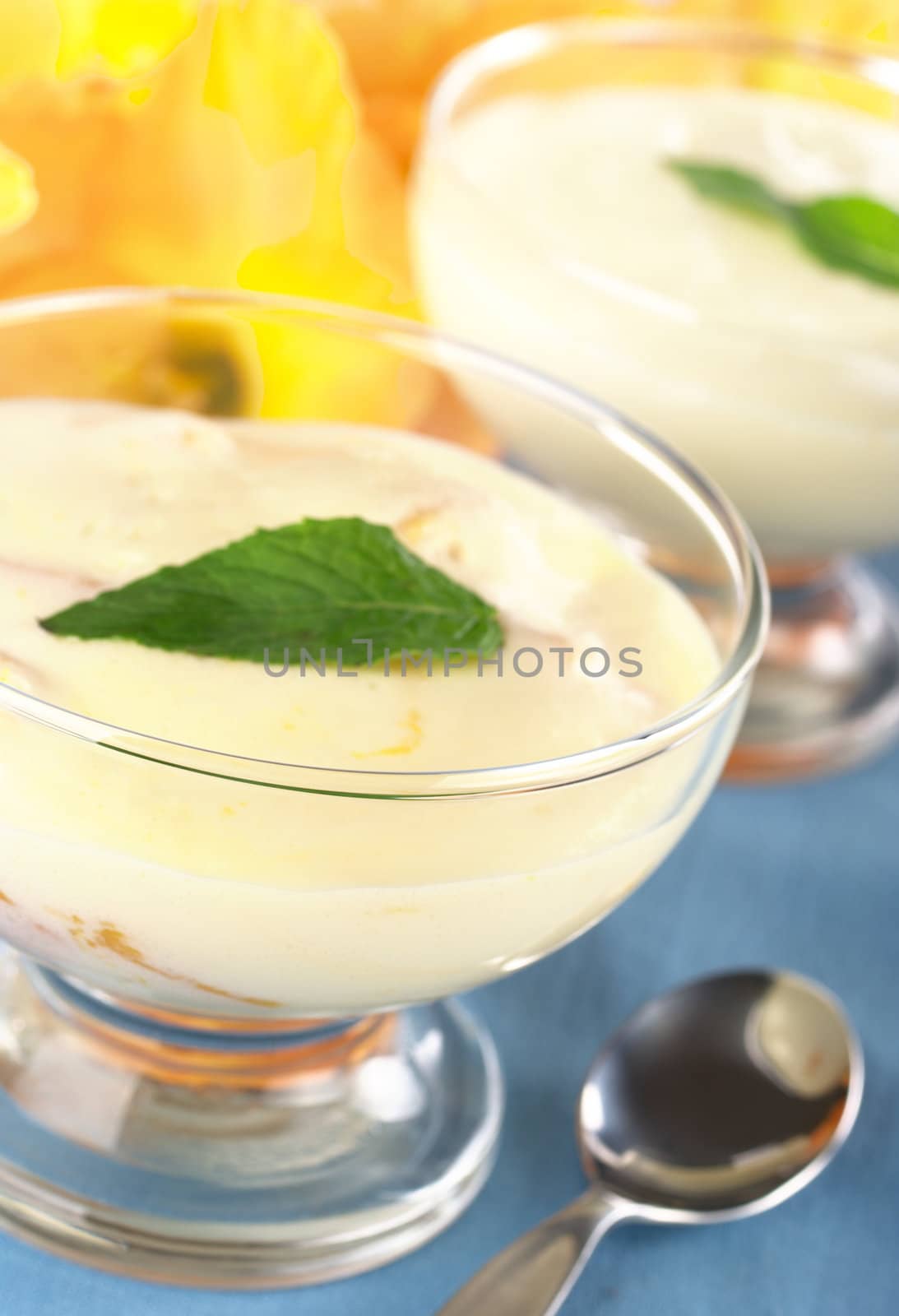 Cream cheese dessert garnished with mint leaf (Selective Focus, Focus on the front glass rim)