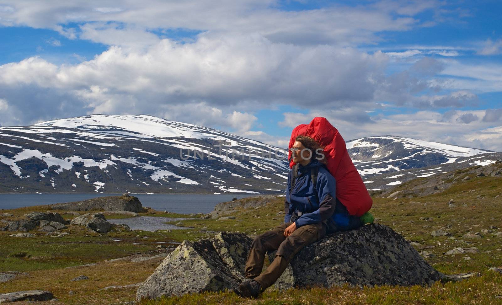 Young hiker resting on rock and enjoying the beautiful landscape along the Nordkalottleden in Northern Norway