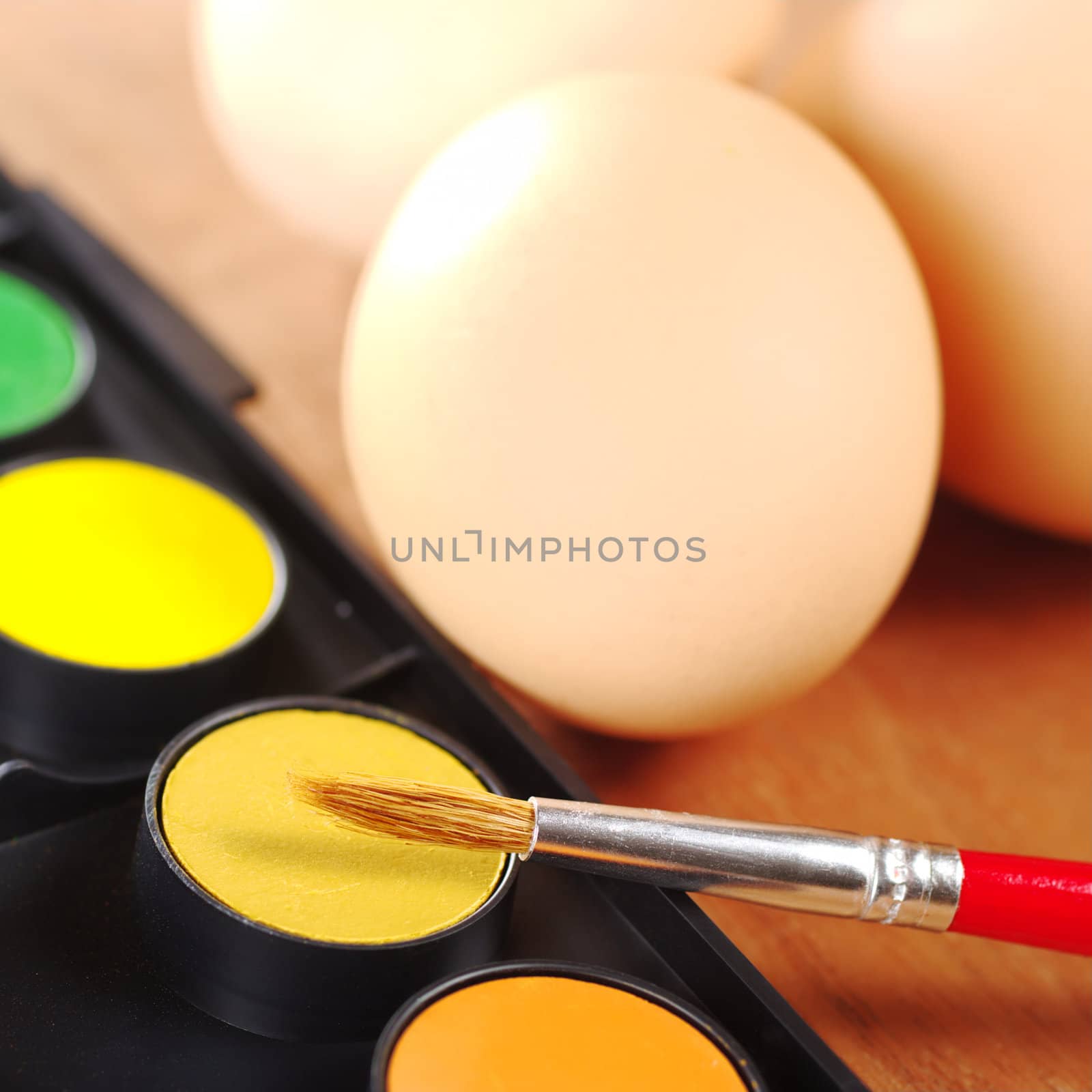Painting Easter eggs: Brush on colors with eggs in the background (Selective Focus, Focus on the brush)