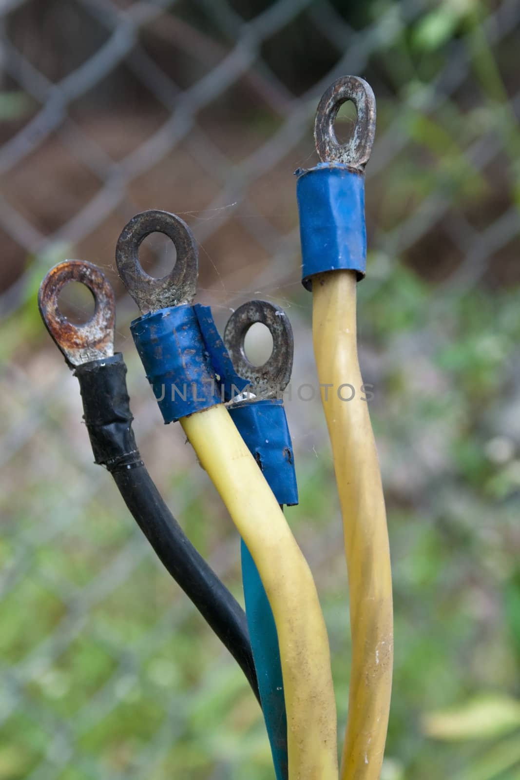 bare electricity cable connectors by the roadside, wire fence backdrop