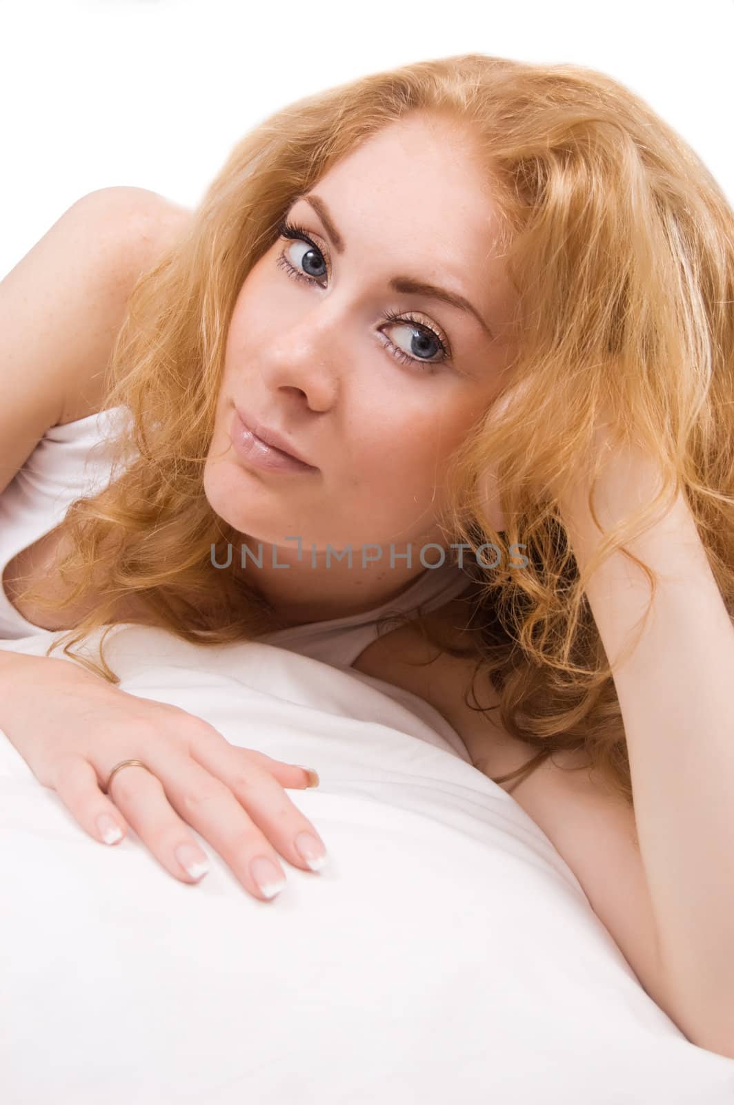 Redheaded woman lying on pillow over white