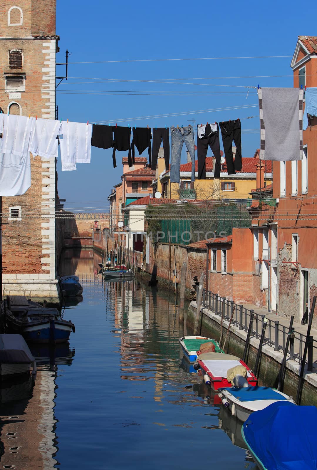 Specific canal with parked boats,specific architecture and clothes hanging out to dry in Venice,Italy.