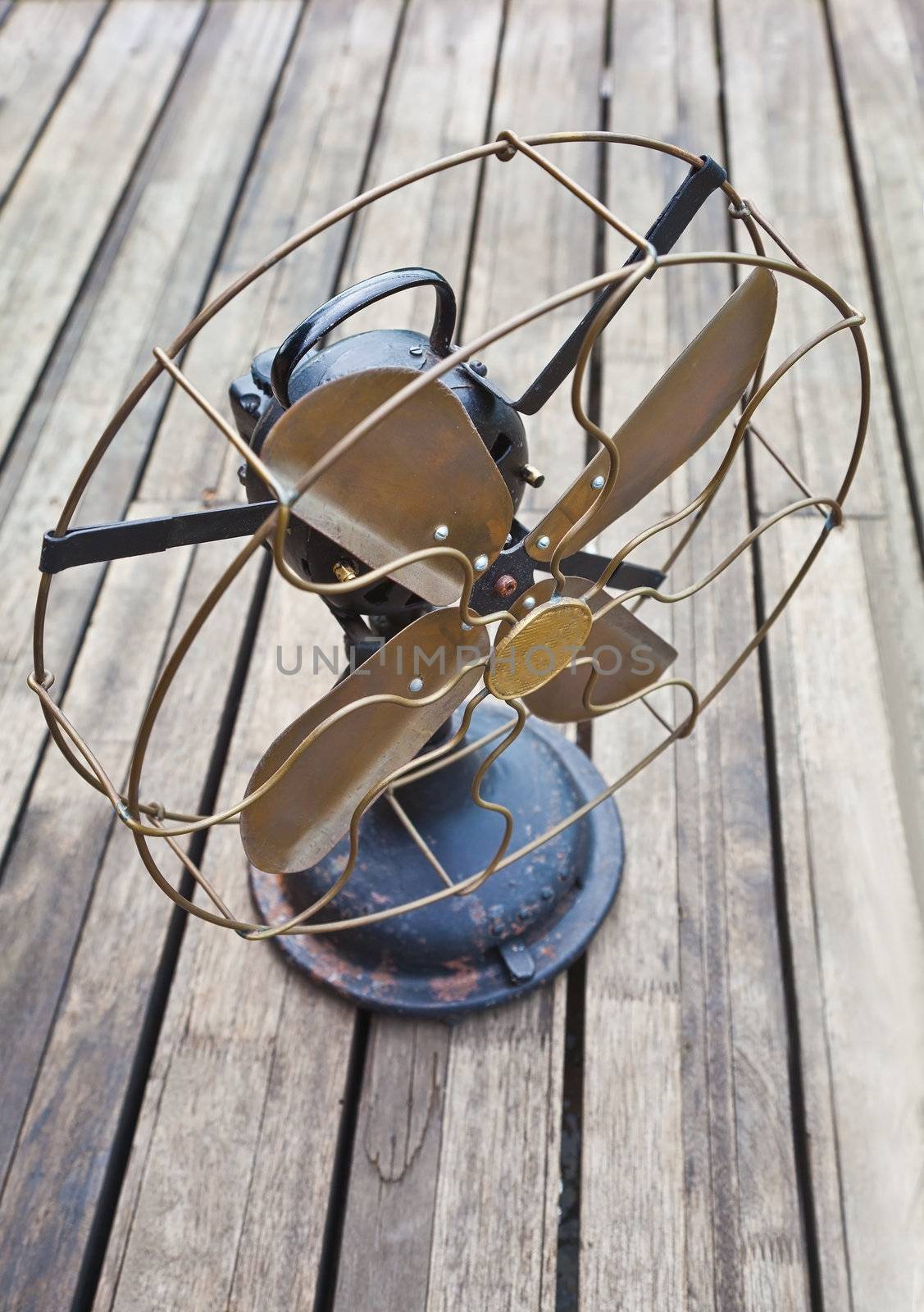old antiquated electric fan on seasoned and soiled wooden decking