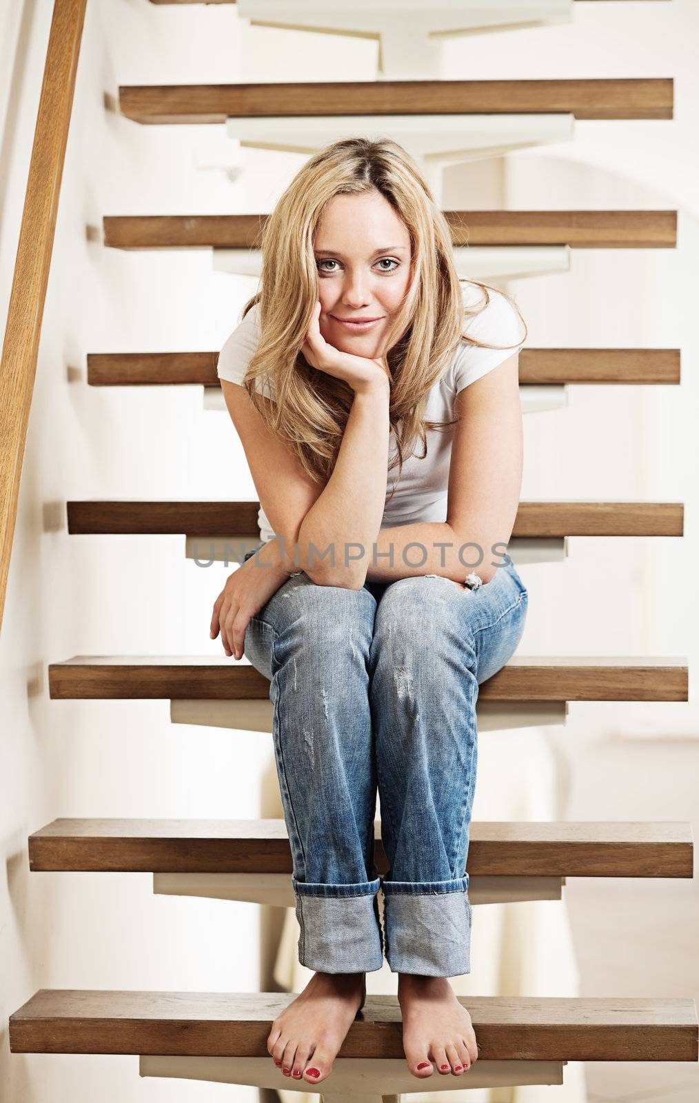 Pretty young smiling woman sitting on steps at home