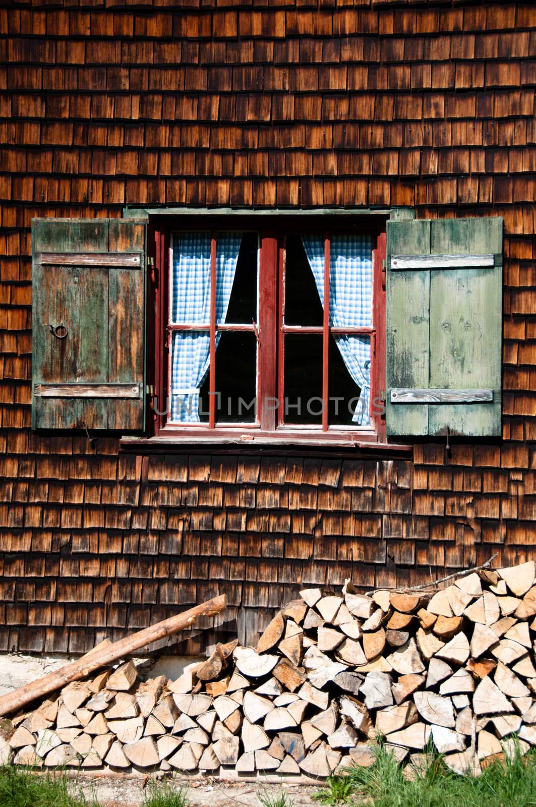Beautiful ancient window on log house with wooden wall and blue curtains