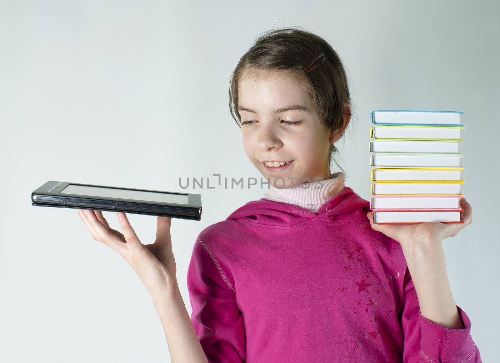 Teen girl holds electronic book in one hand and a stack of books in other