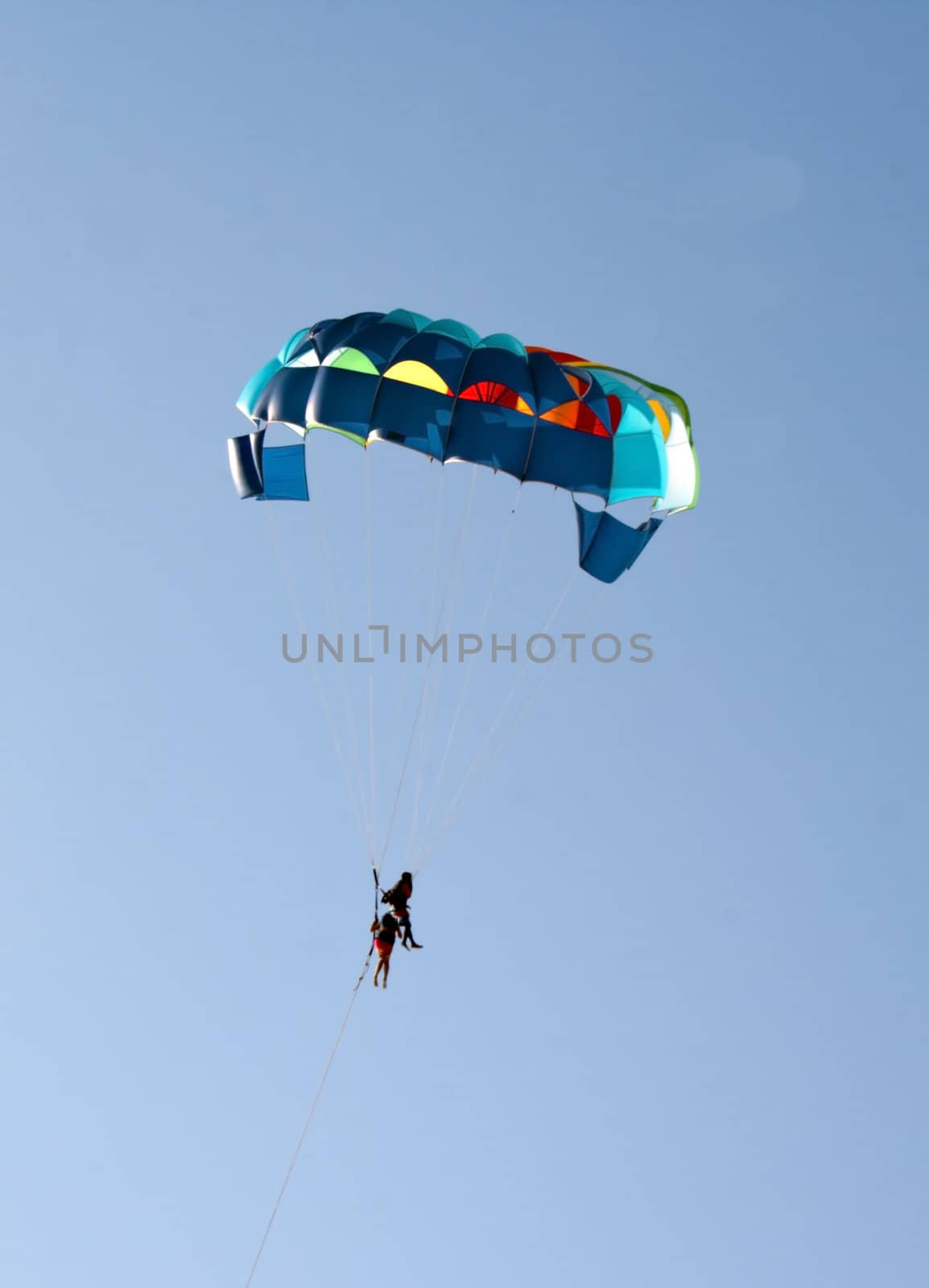 paragliders sailing in blue sky with colourful parachute goa india