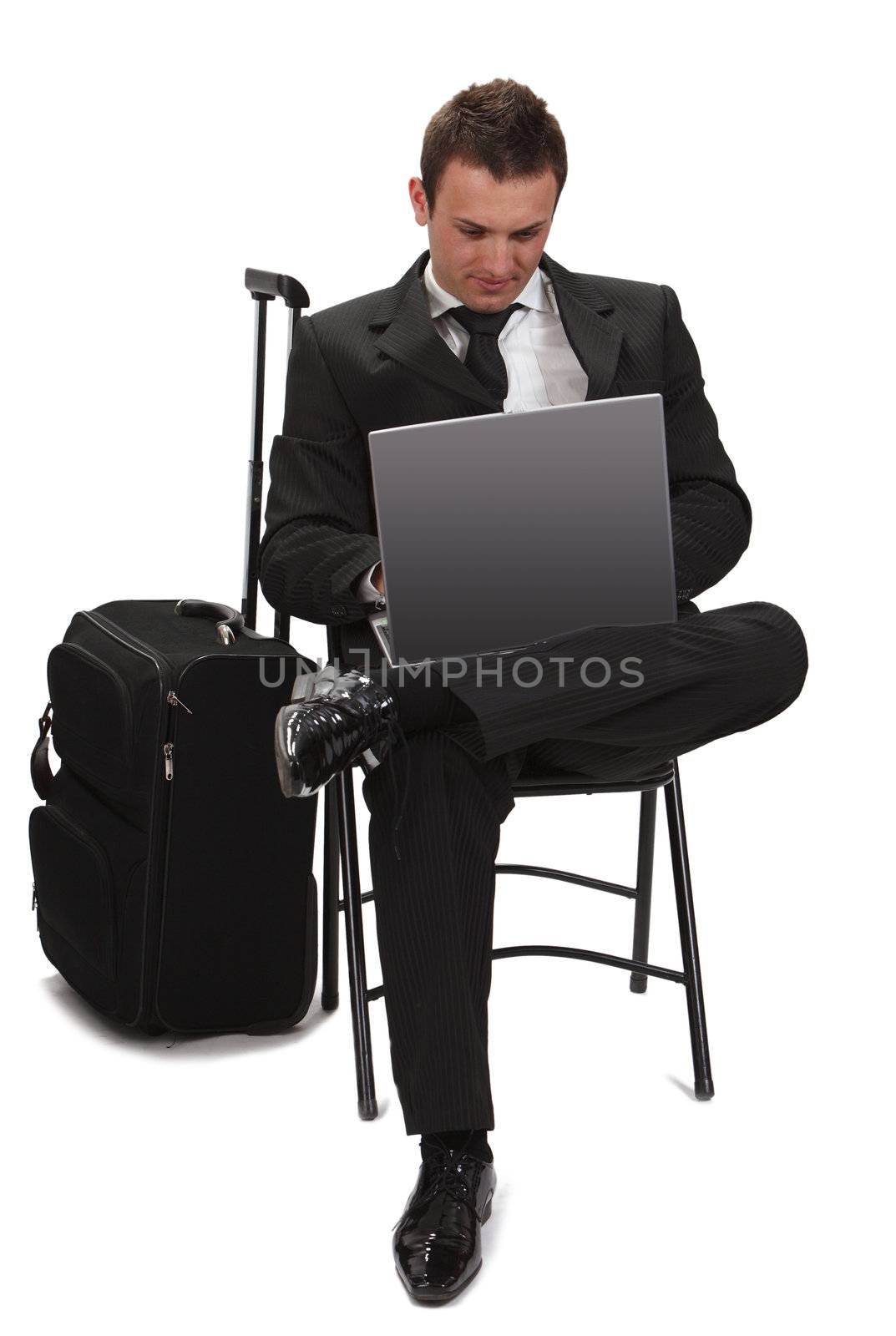 Young traveler businessman working on a laptop next to his suitcase.
