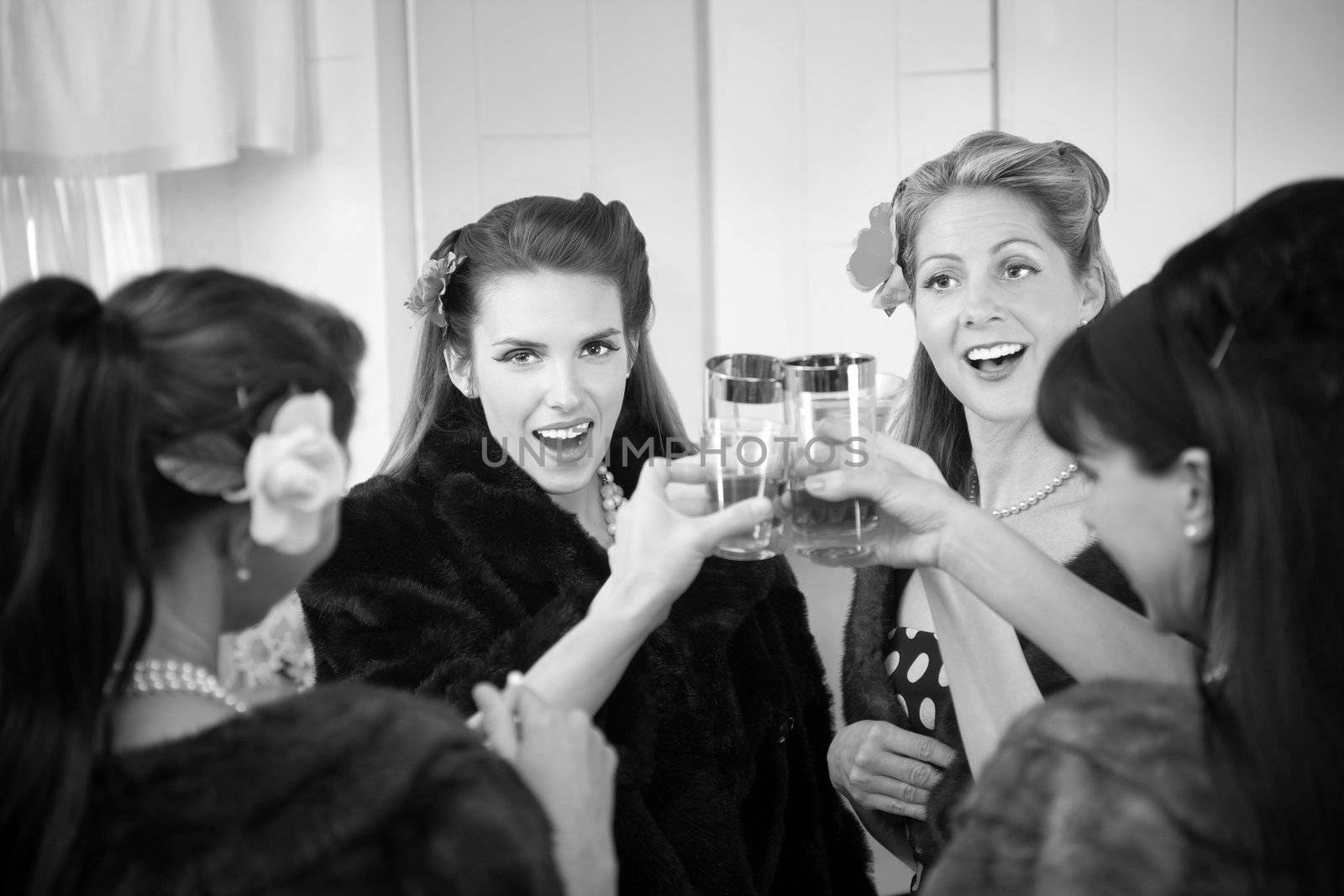 Group of four Caucasian housewives raise a toast in a kitchen