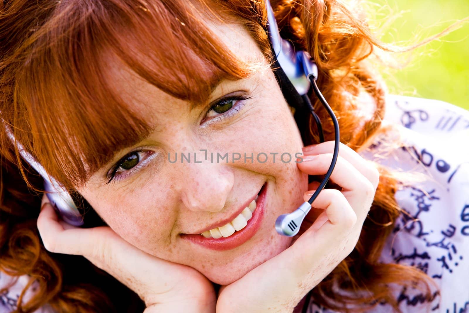 Close-up portrait of red-haired lovely young woman with headset outdoors 